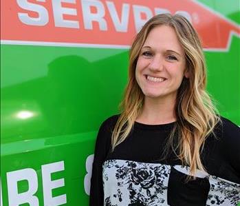 Female employee standing in front of green SERVPRO van