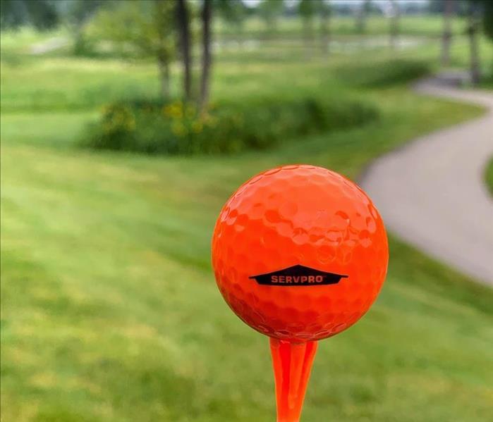 SERVPRO orange golf ball on orange tee in front of trees