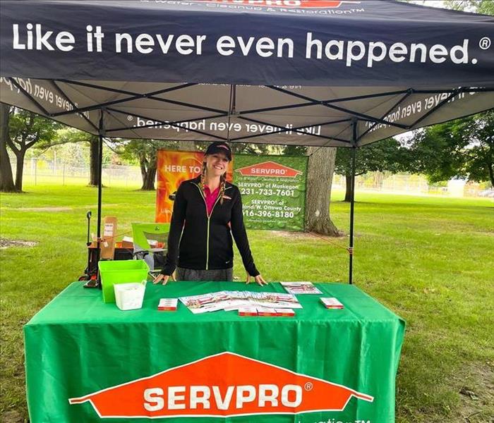 SERVPRO employee standing behind display table under SERVPRO tent