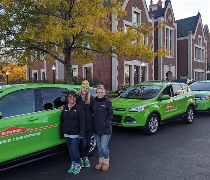 SERVPRO Marketing Gals standing in front of three green SERVPRO cars