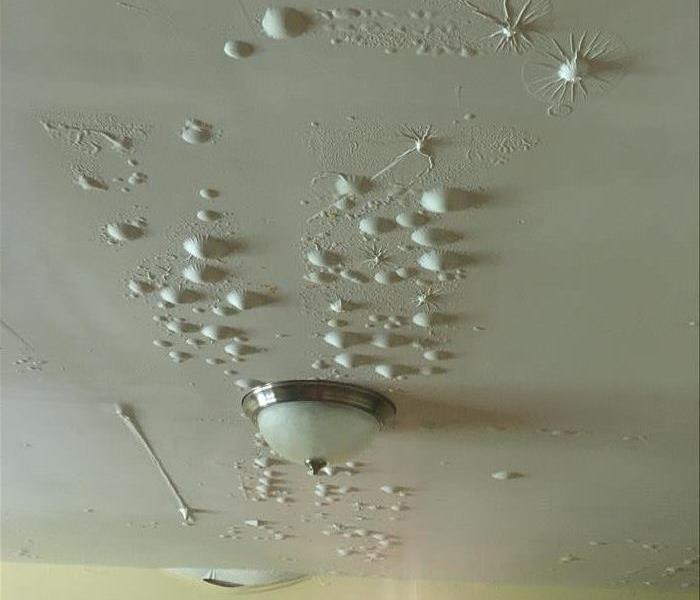 Ceiling bubbling from moisture after water damage.
