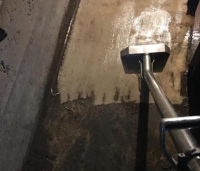 SERVPRO technician steaming sewage on concrete basement floor
